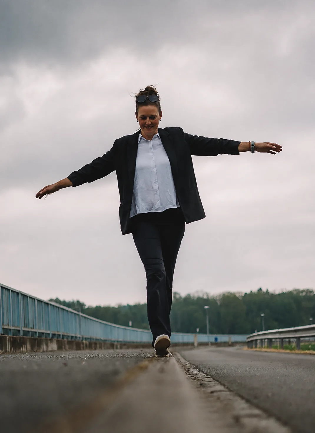 Pavla Weberová kráča s rozpaženými rukami po hrádzi pod zamračenou oblohou.
